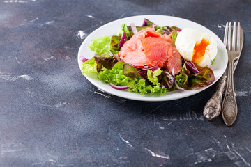 Healthy food - vegetables and salmon salad on a dark background. Selective focus. Copy space