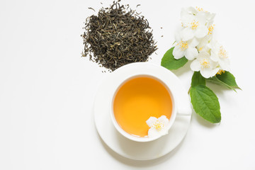 Jasmine dry green tea leaves with jasmine flowers and cup of tea on white background. Copy space...