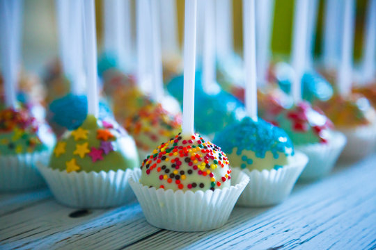 Colorful baked cakepops on white wooden background