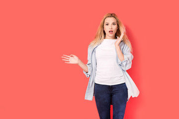 Young blonde girl  with a surprised look on red background