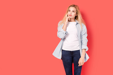 Young blonde girl with a pensive look on red background