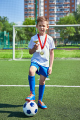 Winner boy football player with cup and medal