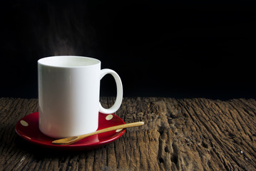 hot white coffee mug with red dish and wood spoon on black background