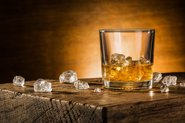 Glass of whiskey on wooden background