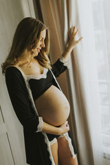 Pregnant woman wearing lingerie and posing in the room