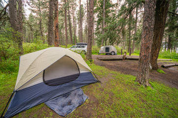 Grey tent and teardrop on a background of the green forest. White car on the camping.  Kamiak Butte State Park Campground,  Whitman County, Washington, USA  