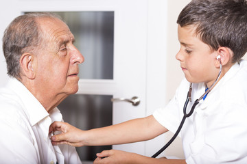 Fototapeta premium Kid examines his grandfather using stethoscope