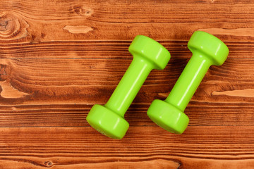 weight concept, green dumbbells on brown vintage wooden