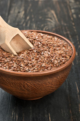 Flax seeds in bowl with scoop on the table closeup
