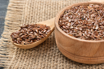 Flax seeds in bowl and spoon on sackcloth closeup