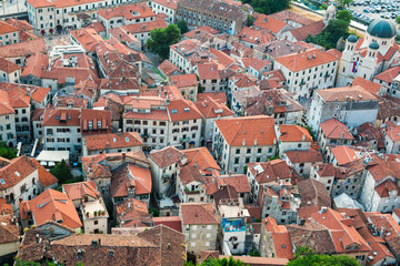 Fototapeta na wymiar View of tiled roofs of old town ang the church from the fortress on the hill in Kotor in Montenegro