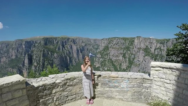 happy little girl waves with a Greek flag on Vikos gorge Zagoria