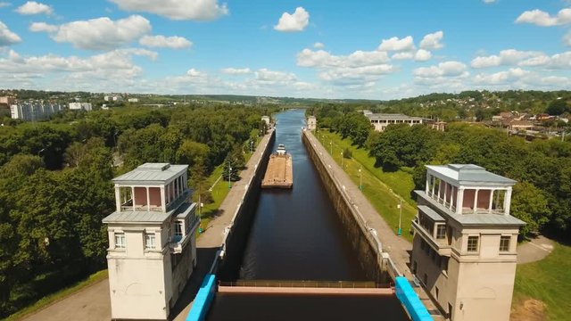 Sluice Gates on the River. Aerial view barge, ship in the river gateway. River sluice construction, water river gateway. Shipping channel. 4K, flying video, aerial footage