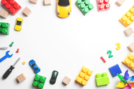Kids toys frame with construction blocks, cubes, toy tools and cars on white background. Top view.