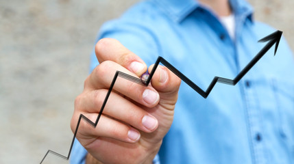 Businessman drawing hand-drawn arrow going up