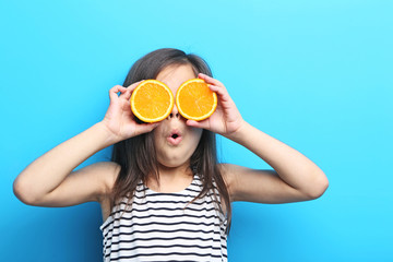 Beautiful little girl with orange on blue background