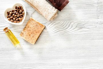 Organic coffee soap, coffee grains, oil and towel on wooden background top view copyspace