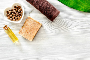 Organic coffee soap, coffee grains, oil and towel on wooden background top view copyspace