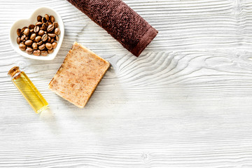 Organic coffee soap, coffee grains, oil and towel on wooden background top view copyspace