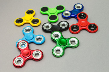 Many colourful fidget finger spinner stress on grey background.