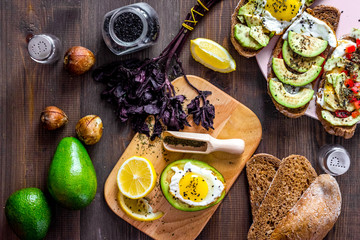 Sandwiches for breakfast with avocado, fried eggs and lemon juice on wooden table top view
