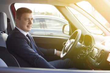 Fototapeta premium Businessman sitting in his car in a highway jam. Looking in the distance while in traffic. Suit and tie businessman sitting in his automobile.