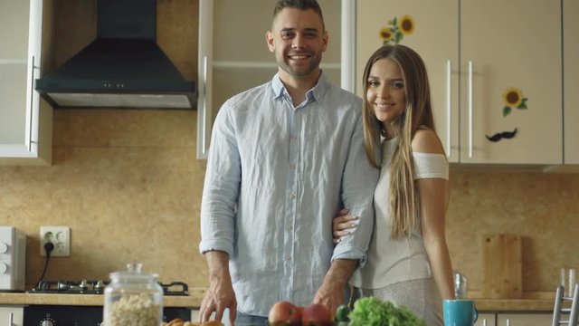 Portrait of loving couple smiling ang looking into camera in the kitchen at home
