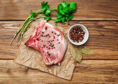 A piece of raw meat, pork with vegetables and spices on a dark, wooden background. Banner for the restaurant.