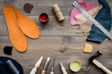 Working place of shoemaker. Skin and tools on brown wooden desk background top view copypace