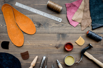 Working place of shoemaker. Skin and tools on brown wooden desk background top view copypace