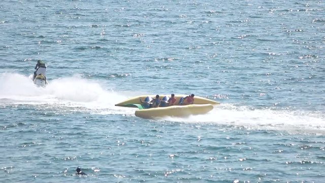 Flying banana boat, jet ski. People and sparkling sea.
