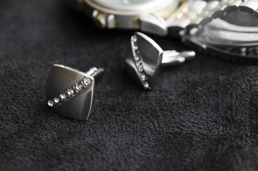 Silver cufflinks with crystals lie on a black canvas