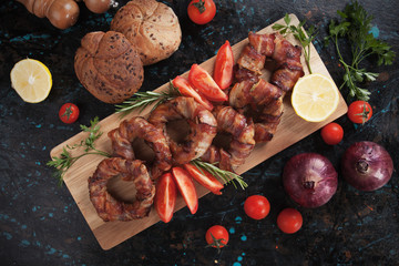 Grilled bacon rings on wooden board