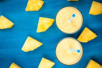 pineapple juice in a glass and pineapple fruits lying around top view