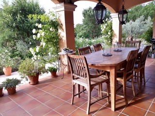 Fototapeta na wymiar Cosy, french patio in provence with wooden garden furniture, surrounded by beautiful, white roses