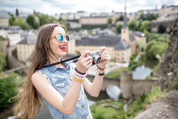 Young female traveler with photocamera enjoying beautiful cityscape view on the old town in Luxembourg city