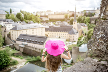 Fototapeta premium Female traveler standing back with pink hat and enjoy beautiful cityscape view on the old town in Luxembourg city