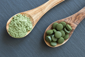 Chlorella and young barley powder on two wooden spoons