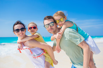 Happy beautiful family of four on a tropical beach. Parents and kids background seashore on beach vacation