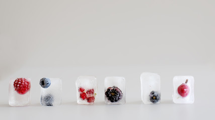 Ice cubes with frozen berries - blackberries, raspberries, black currants, blueberries and lemon.