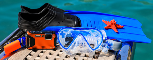 Mask, fins, underwater camera, starfish on the sea background.