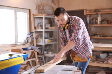 Carpenter sawing timber in workshop