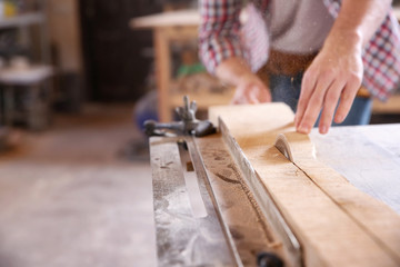 Carpenter sawing timber in workshop