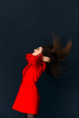 Model wearing red coat shaking her head on dark background