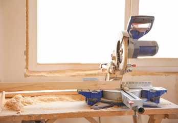 Circular saw and timber strip on table near window in carpenter's workshop