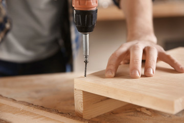 Carpenter driving screw nail into timber in workshop