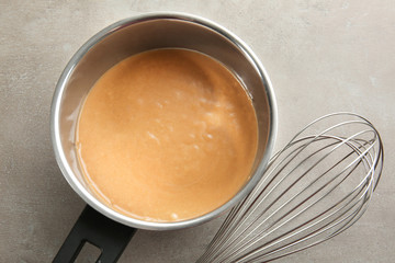 Delicious turkey gravy in saucepan on grey table