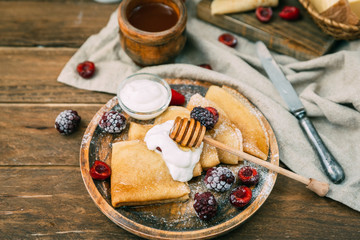 Homemade pancakes with honey and butter over wooden rustic background