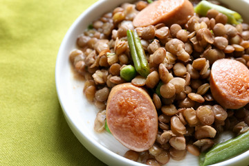 Plate with tasty lentil porridge, sausages and vegetables on table, closeup