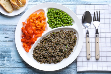 Composition with tasty lentil porridge and vegetables on wooden table